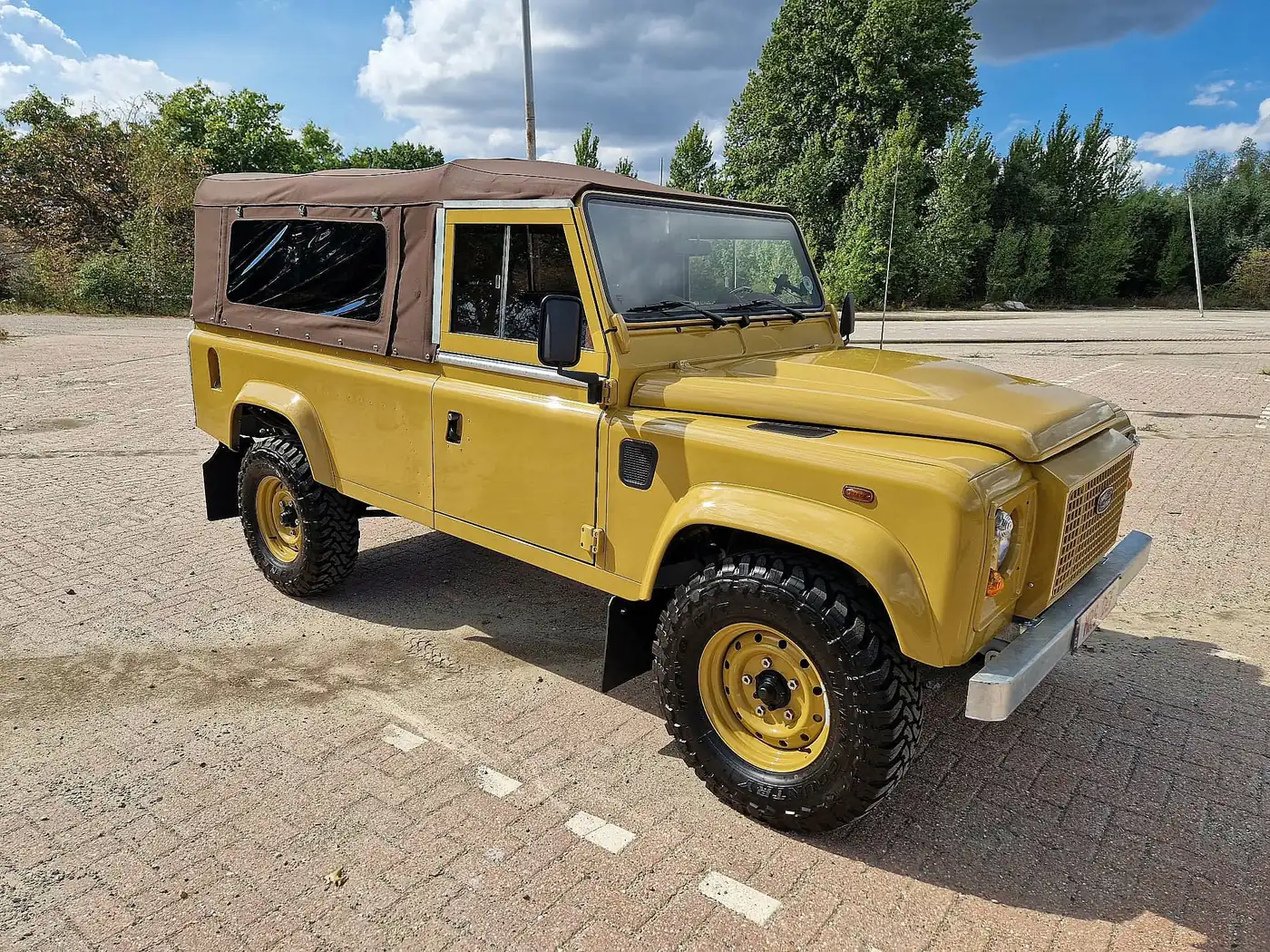 Land Rover Defender 110 soft top in zandgeel, opgebouwd door Desert Foxx