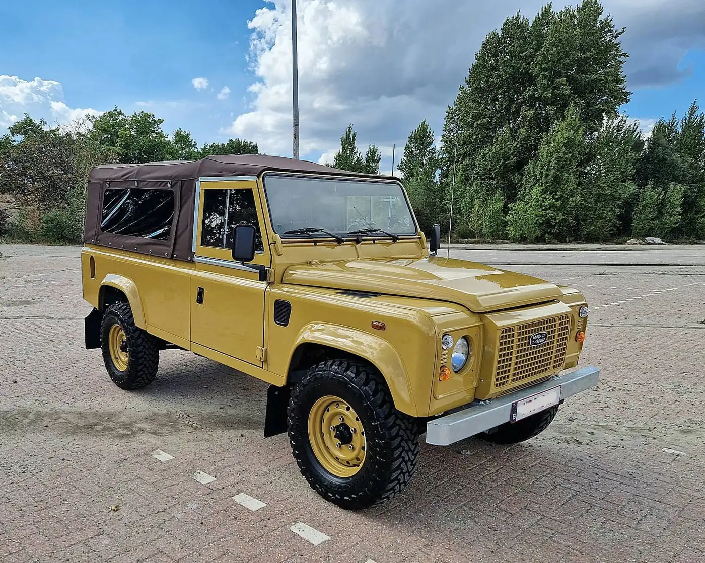 Land Rover Defender 110 soft top in zandgeel, opgebouwd door Desert Foxx