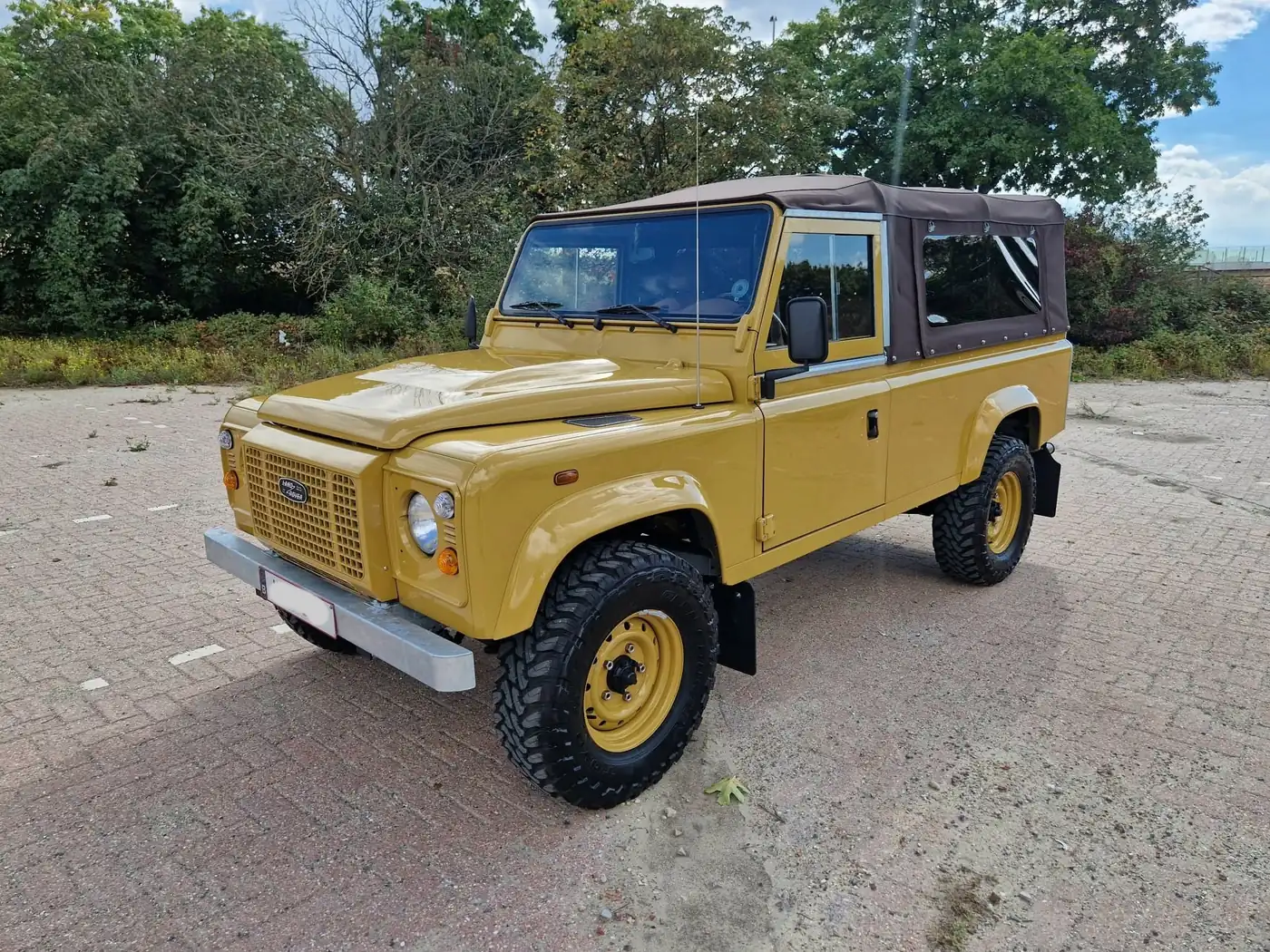 Land Rover Defender 110 soft top in zandgeel, opgebouwd door Desert Foxx