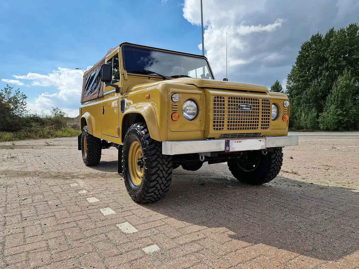 Land Rover Defender 110 soft top in zandgeel, opgebouwd door Desert Foxx
